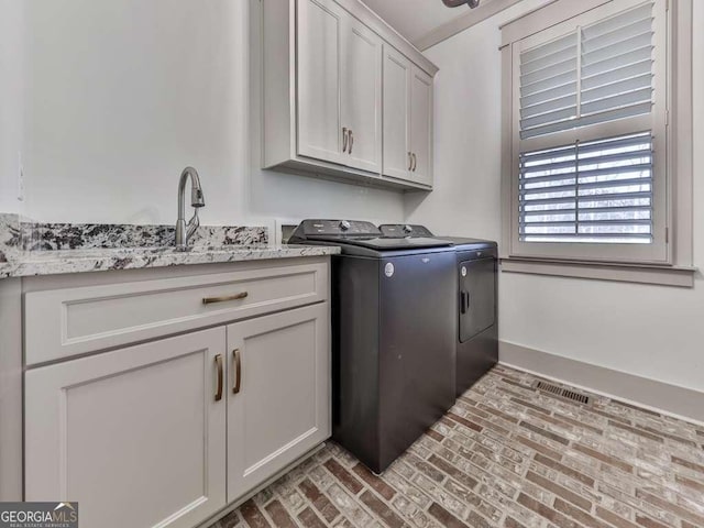 laundry room featuring sink, washing machine and dryer, and cabinets