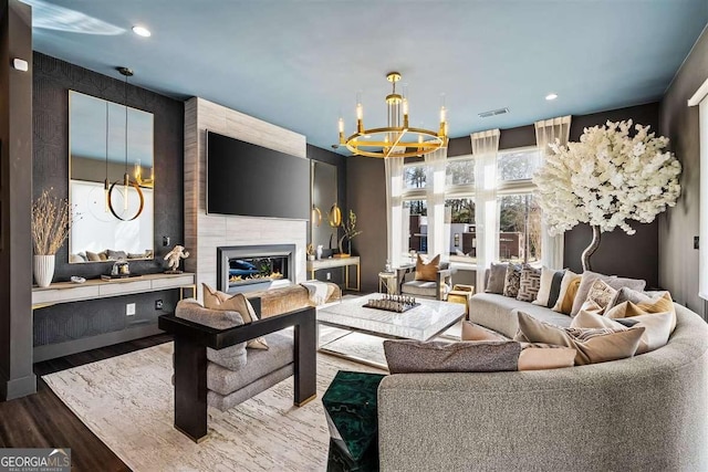 living room with hardwood / wood-style floors, a notable chandelier, and a fireplace