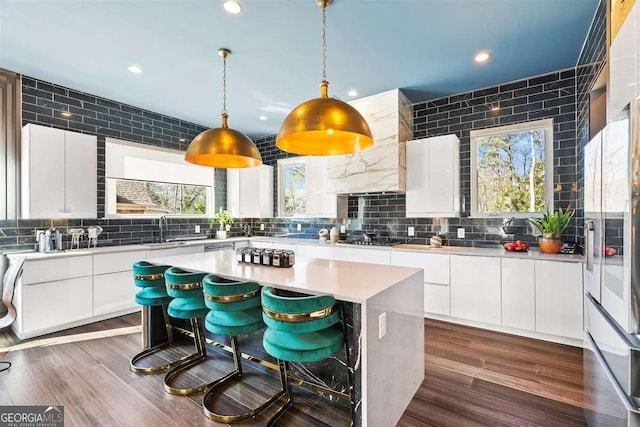 kitchen with dark hardwood / wood-style floors, decorative light fixtures, tasteful backsplash, white cabinetry, and a center island