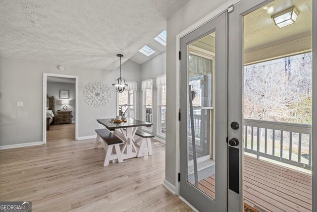 dining space featuring an inviting chandelier, a textured ceiling, french doors, and light wood-type flooring