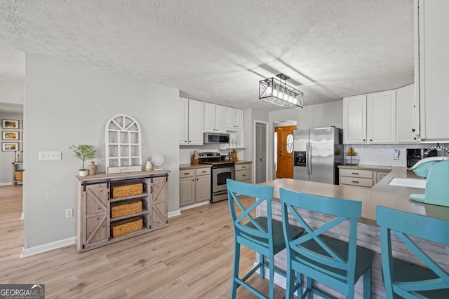 kitchen featuring appliances with stainless steel finishes, white cabinets, and light wood-type flooring