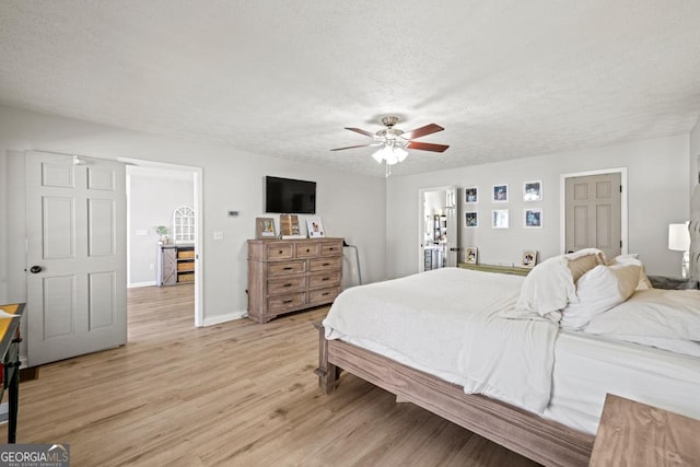 bedroom with ceiling fan, a textured ceiling, and light wood-type flooring