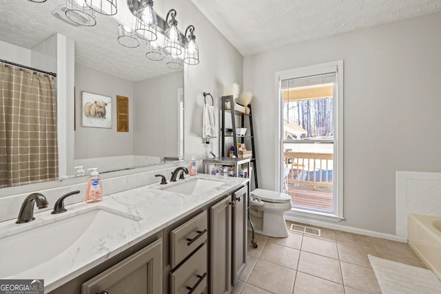 bathroom featuring a bathtub, vanity, a textured ceiling, tile patterned floors, and toilet