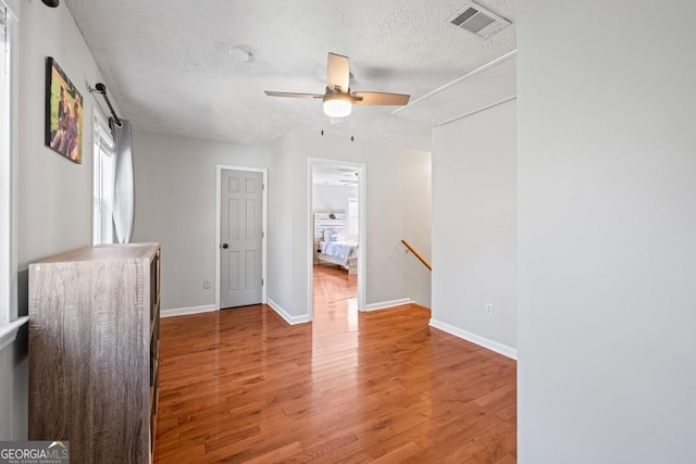 empty room with ceiling fan, hardwood / wood-style floors, and a textured ceiling