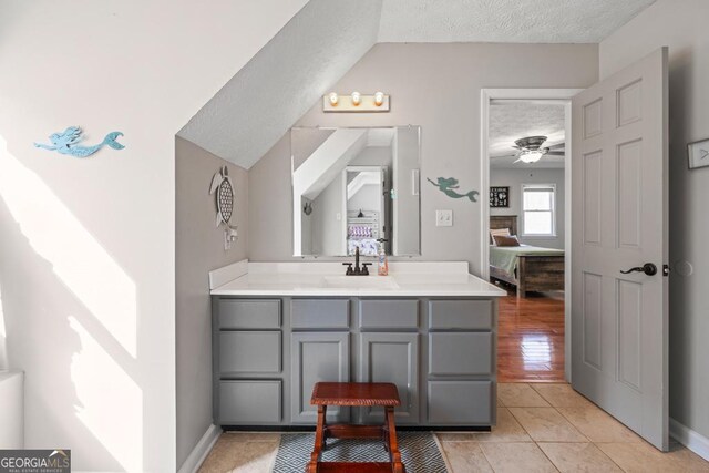 bathroom with ceiling fan, vanity, a textured ceiling, tile patterned floors, and toilet