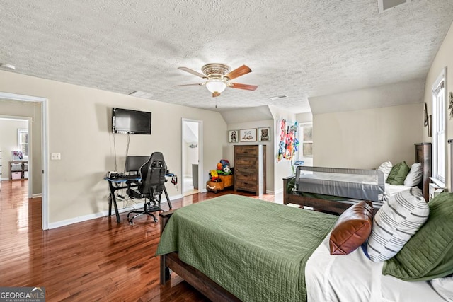 bedroom featuring a walk in closet, wood-type flooring, a textured ceiling, a closet, and ceiling fan