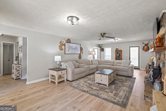 living room featuring ceiling fan, a textured ceiling, and light hardwood / wood-style floors