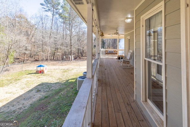 deck with cooling unit, a lawn, and ceiling fan