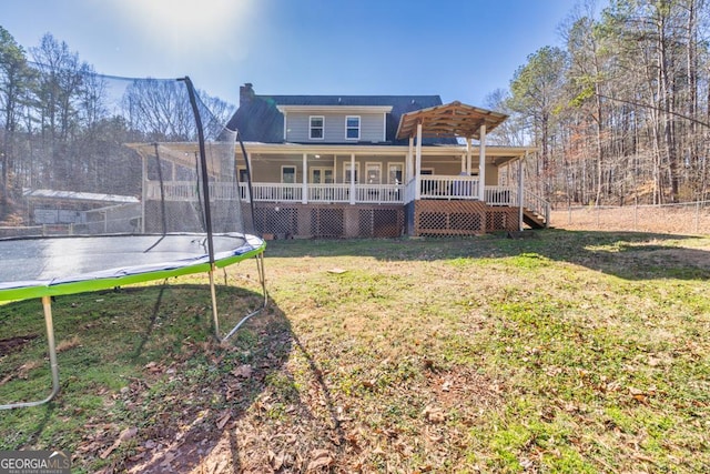 back of house featuring a trampoline, a lawn, and a porch