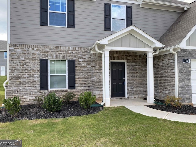 property entrance featuring board and batten siding, a yard, and brick siding