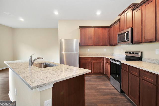 kitchen featuring sink, appliances with stainless steel finishes, dark hardwood / wood-style floors, an island with sink, and light stone countertops