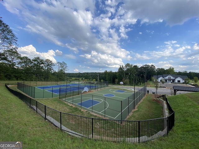 view of sport court featuring tennis court and a lawn