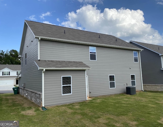 back of property with central AC unit and a lawn