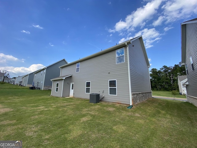 rear view of property with cooling unit and a yard