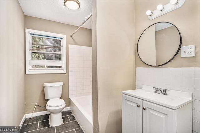 full bathroom with tile patterned floors, toilet, tiled shower / bath, a textured ceiling, and vanity