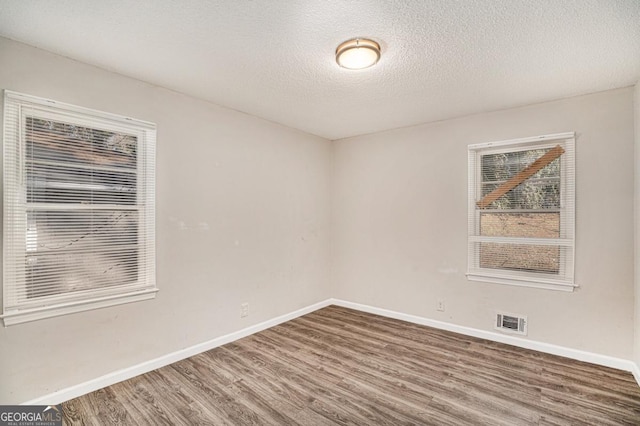 unfurnished room featuring hardwood / wood-style flooring and a textured ceiling