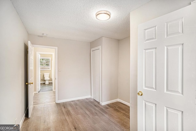 hall with a textured ceiling and light hardwood / wood-style floors