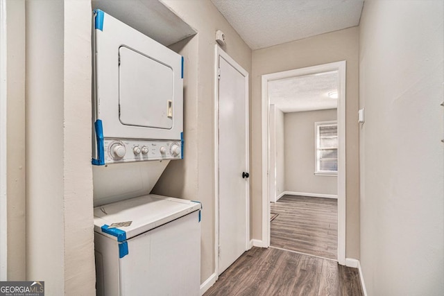 washroom featuring dark hardwood / wood-style flooring, a textured ceiling, and stacked washing maching and dryer