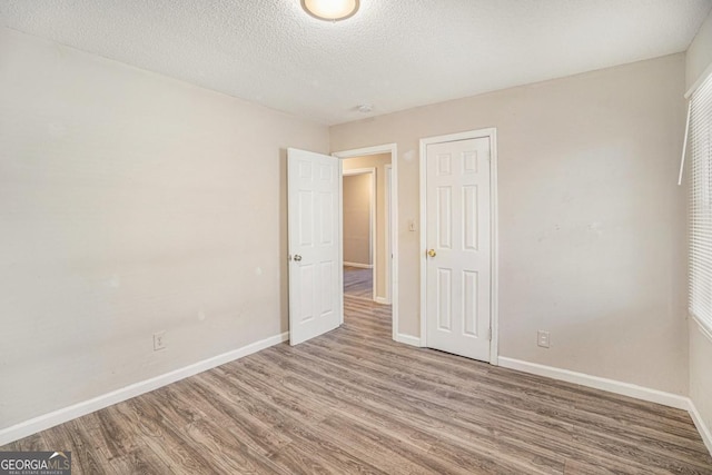 unfurnished room with hardwood / wood-style flooring and a textured ceiling