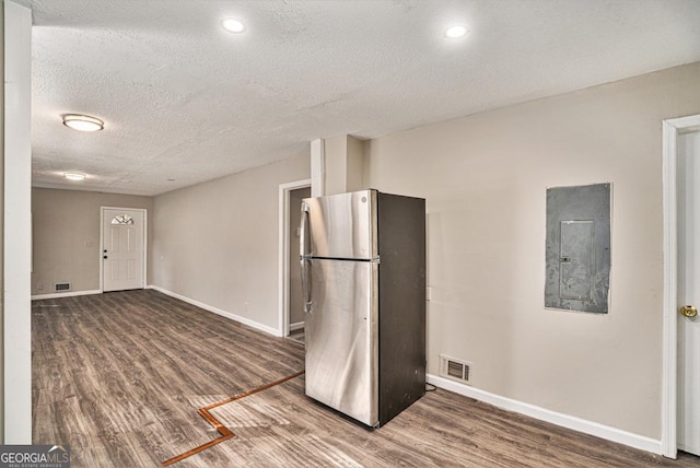 kitchen with hardwood / wood-style flooring, stainless steel fridge, electric panel, and a textured ceiling