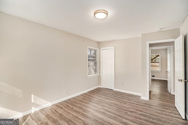 unfurnished room featuring wood-type flooring and a textured ceiling