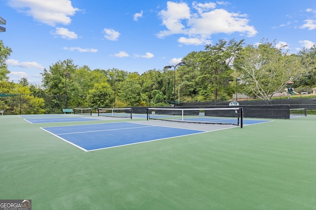 view of tennis court featuring a playground