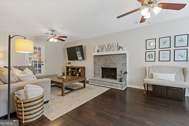 living room featuring ceiling fan, a fireplace, and dark hardwood / wood-style flooring