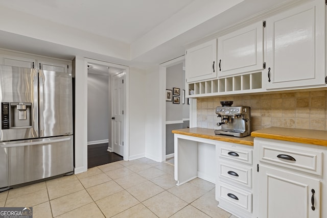 kitchen with light tile patterned floors, white cabinetry, backsplash, butcher block counters, and stainless steel fridge with ice dispenser