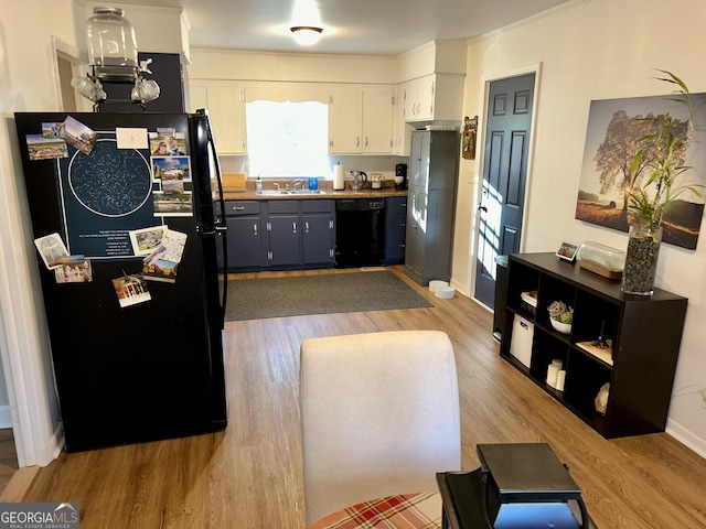 kitchen featuring white cabinetry, sink, light wood-type flooring, and black appliances