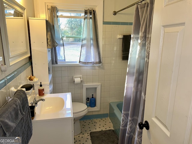 full bathroom featuring tile patterned floors, toilet, tile walls, vanity, and shower / bath combo