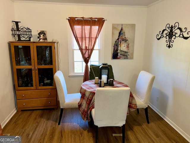 dining area with dark hardwood / wood-style flooring and crown molding