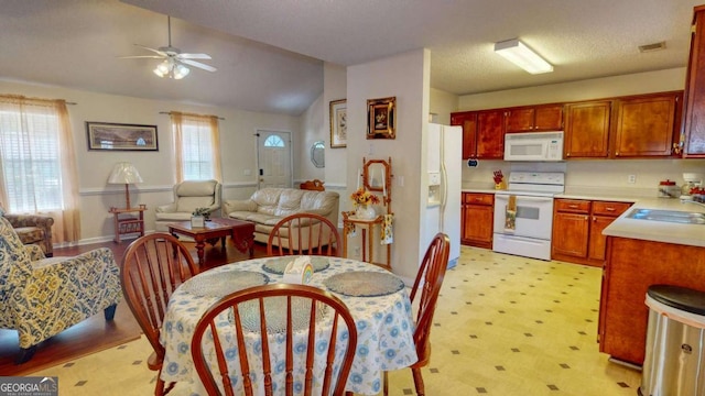 kitchen featuring ceiling fan, white appliances, lofted ceiling, and sink