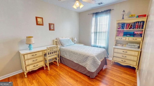 bedroom with ceiling fan, hardwood / wood-style floors, and a textured ceiling