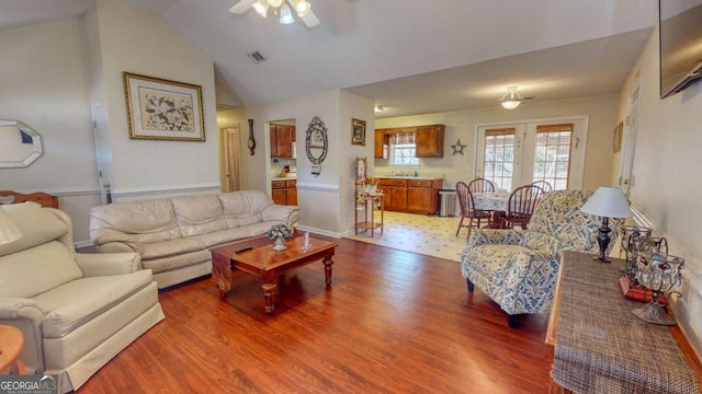 living room featuring hardwood / wood-style flooring, vaulted ceiling, and ceiling fan