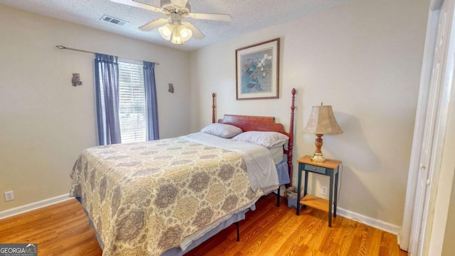 bedroom featuring ceiling fan, wood-type flooring, and a textured ceiling