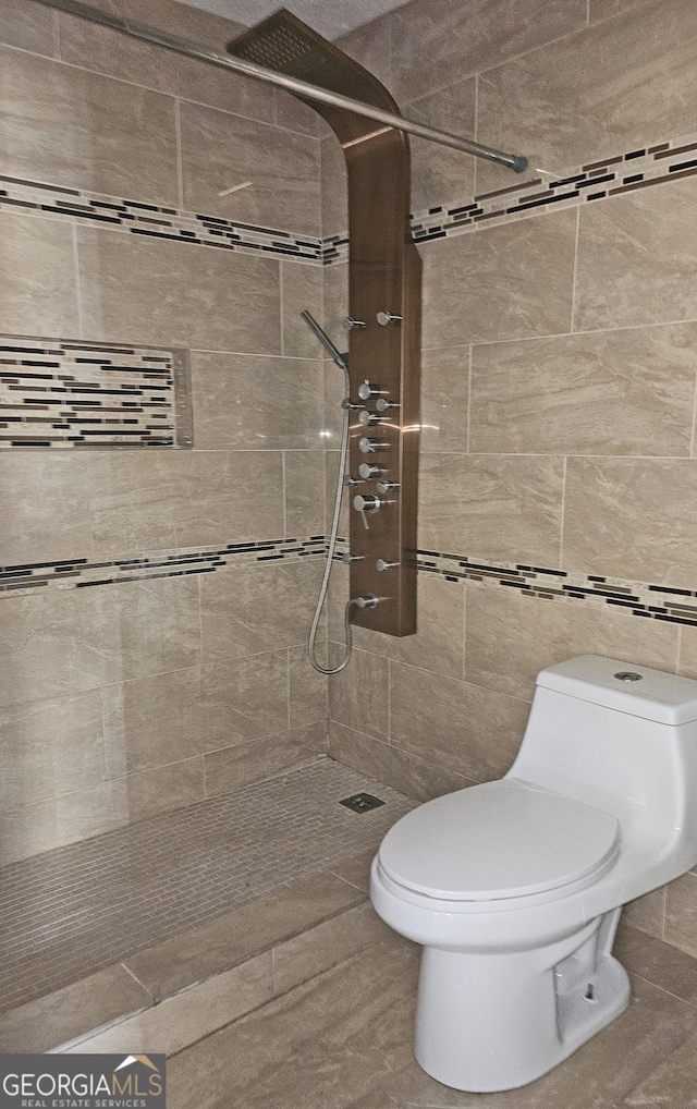 bathroom with tile walls, toilet, and tiled shower