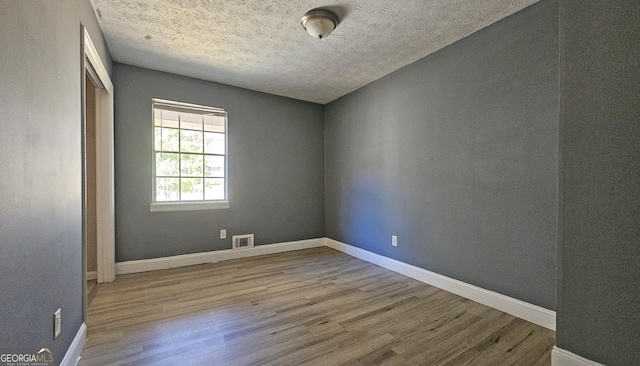 empty room with hardwood / wood-style floors and a textured ceiling