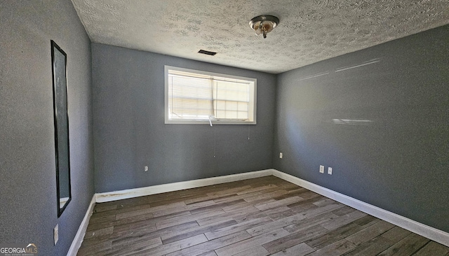 unfurnished room featuring hardwood / wood-style flooring and a textured ceiling