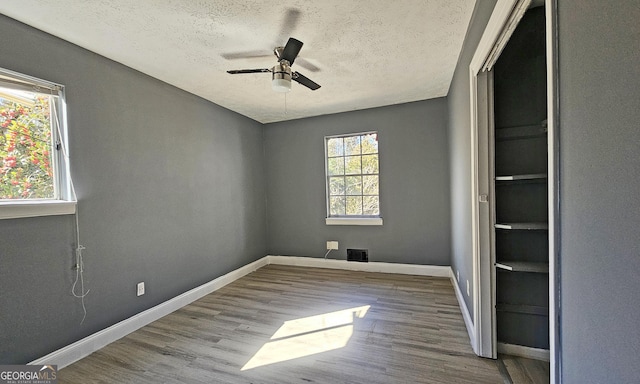 spare room with a healthy amount of sunlight, light hardwood / wood-style floors, and a textured ceiling