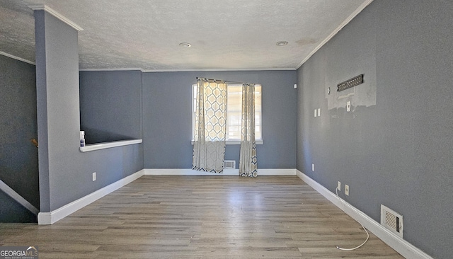 spare room featuring ornamental molding, hardwood / wood-style floors, and a textured ceiling