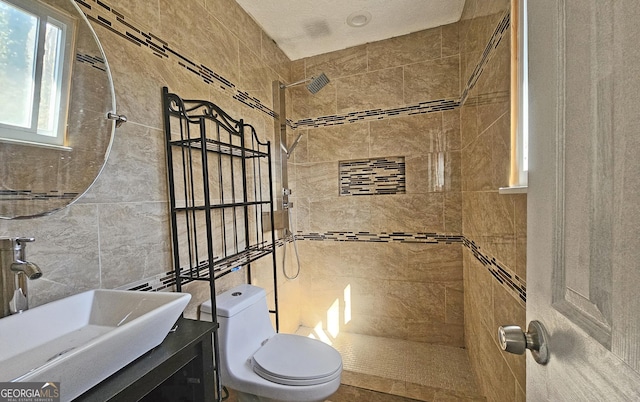 bathroom with tile walls, vanity, toilet, and tiled shower