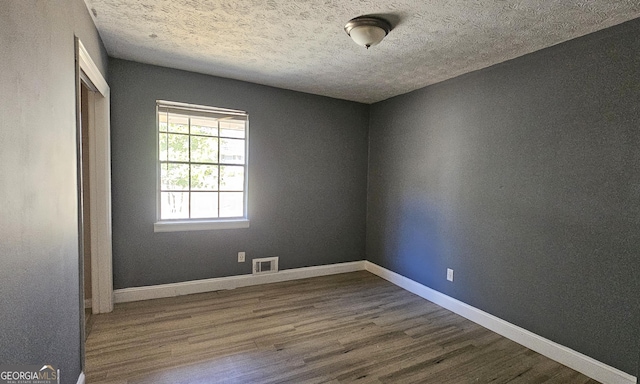 unfurnished room with wood-type flooring and a textured ceiling