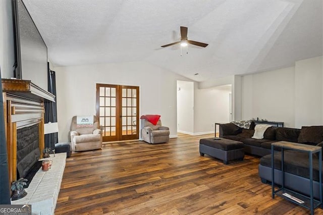 living room featuring a textured ceiling, dark hardwood / wood-style flooring, a brick fireplace, vaulted ceiling, and french doors