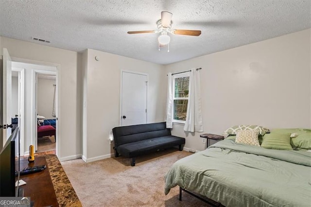 bedroom featuring ceiling fan, light colored carpet, and a textured ceiling