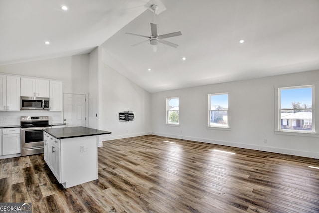 kitchen with appliances with stainless steel finishes, hardwood / wood-style floors, white cabinets, and decorative backsplash