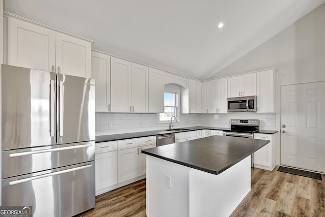 kitchen with stainless steel appliances, white cabinetry, a kitchen island, and sink