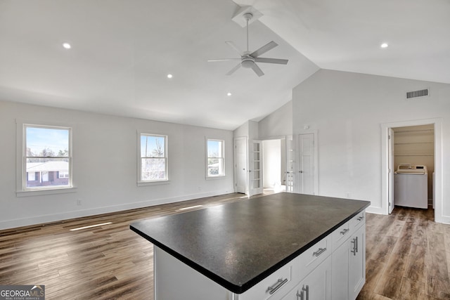 kitchen with washer / clothes dryer, white cabinetry, a center island, and hardwood / wood-style floors