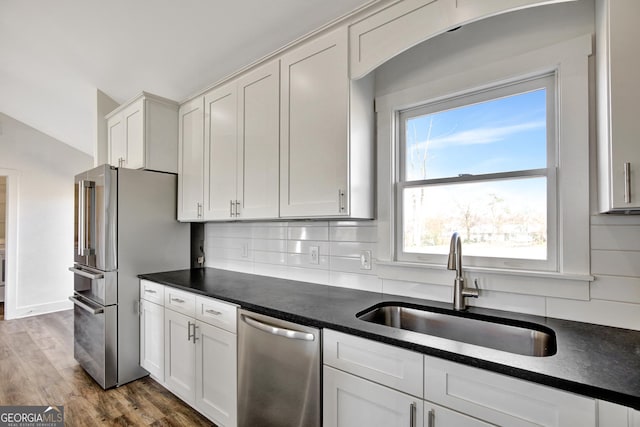 kitchen featuring sink, white cabinets, decorative backsplash, hardwood / wood-style flooring, and stainless steel appliances