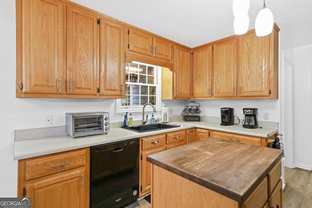 kitchen featuring a kitchen island, decorative light fixtures, black dishwasher, sink, and light hardwood / wood-style flooring