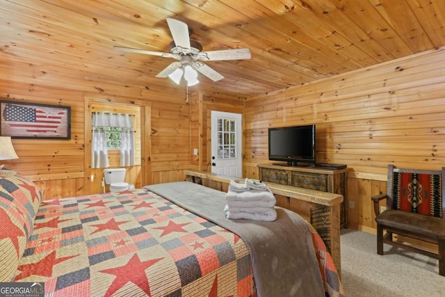 carpeted bedroom featuring wooden ceiling, ceiling fan, and wood walls